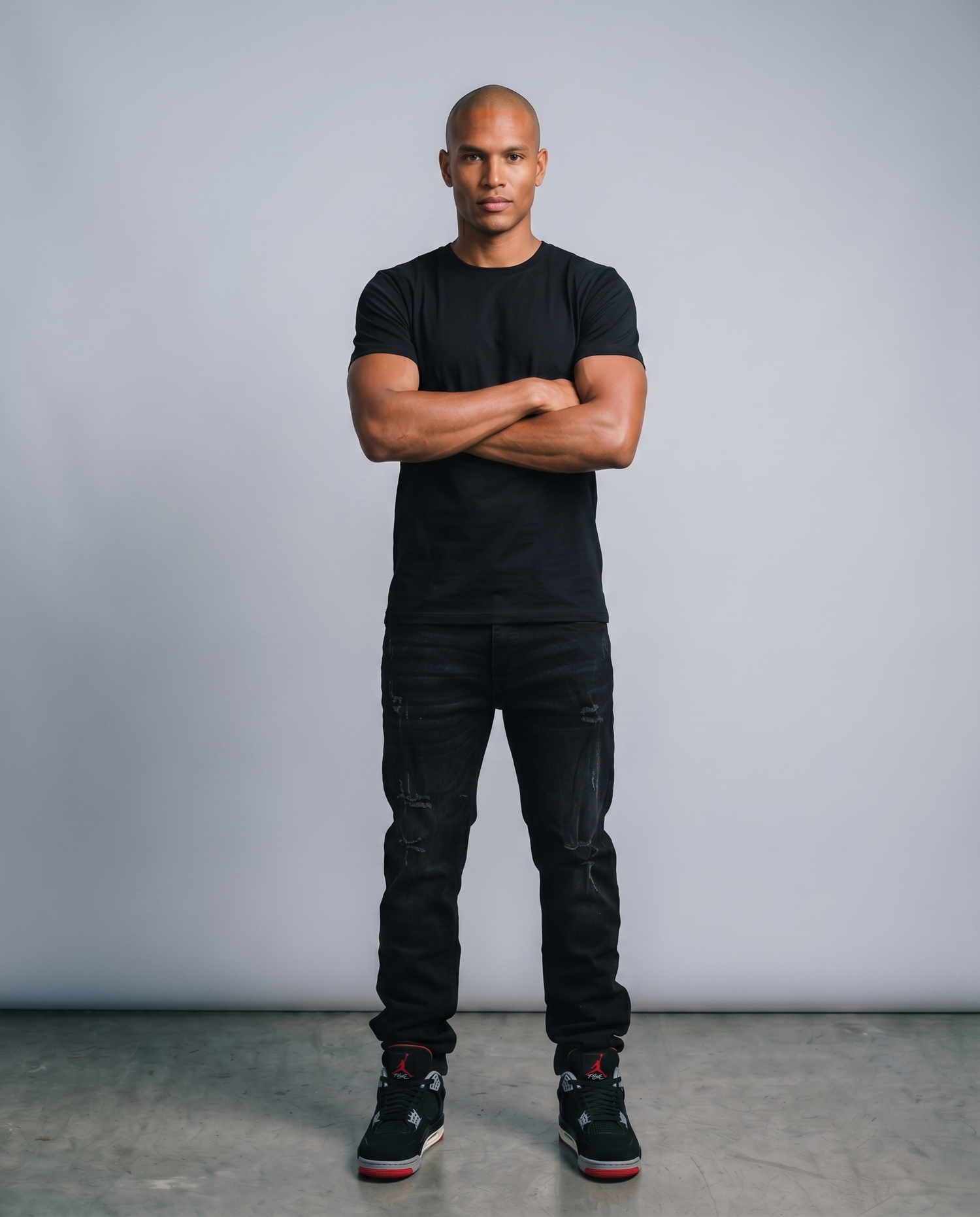 Man wearing a black t-shirt and black pants standing against a gray background