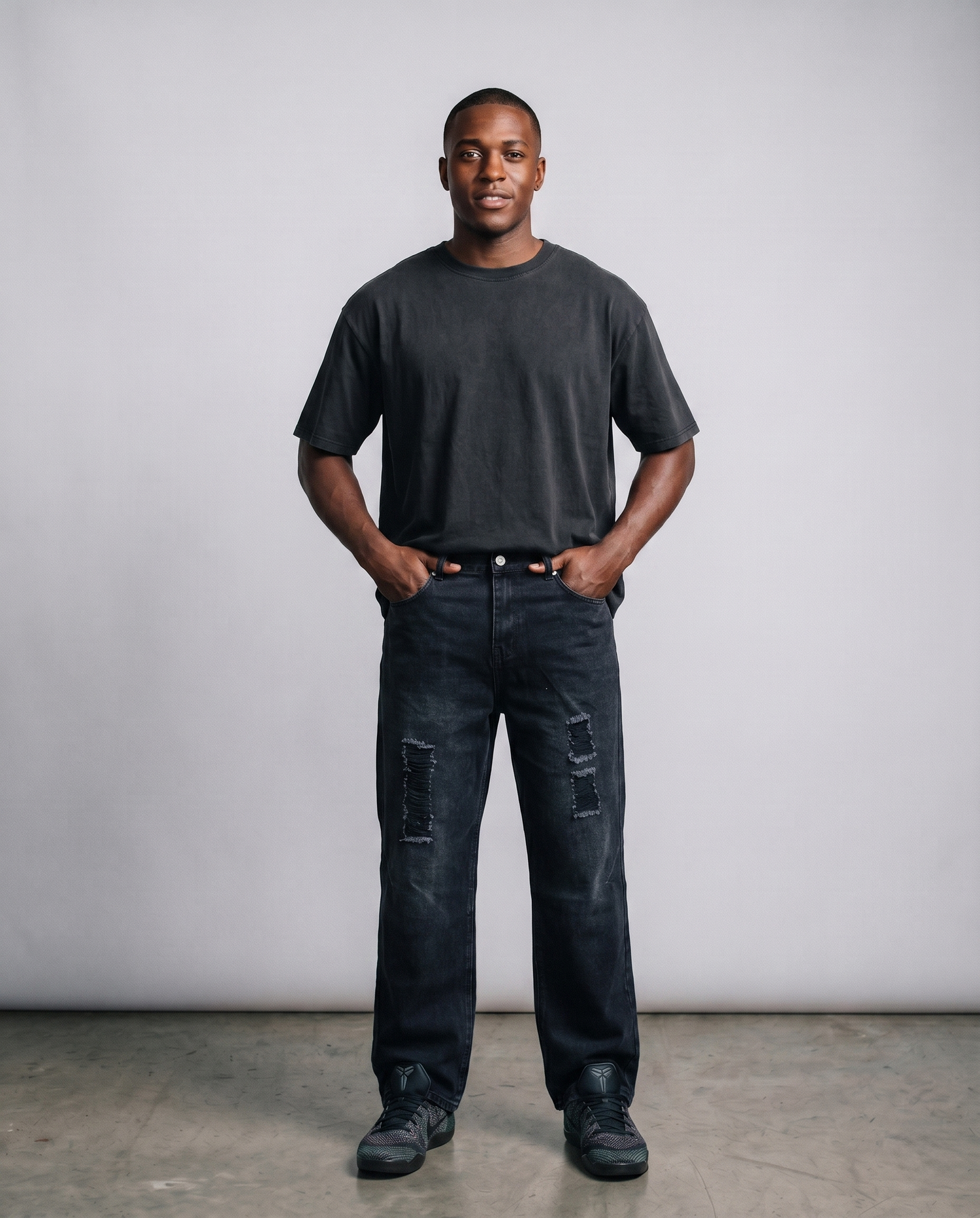 Man wearing a black t-shirt and dark jeans against a plain background