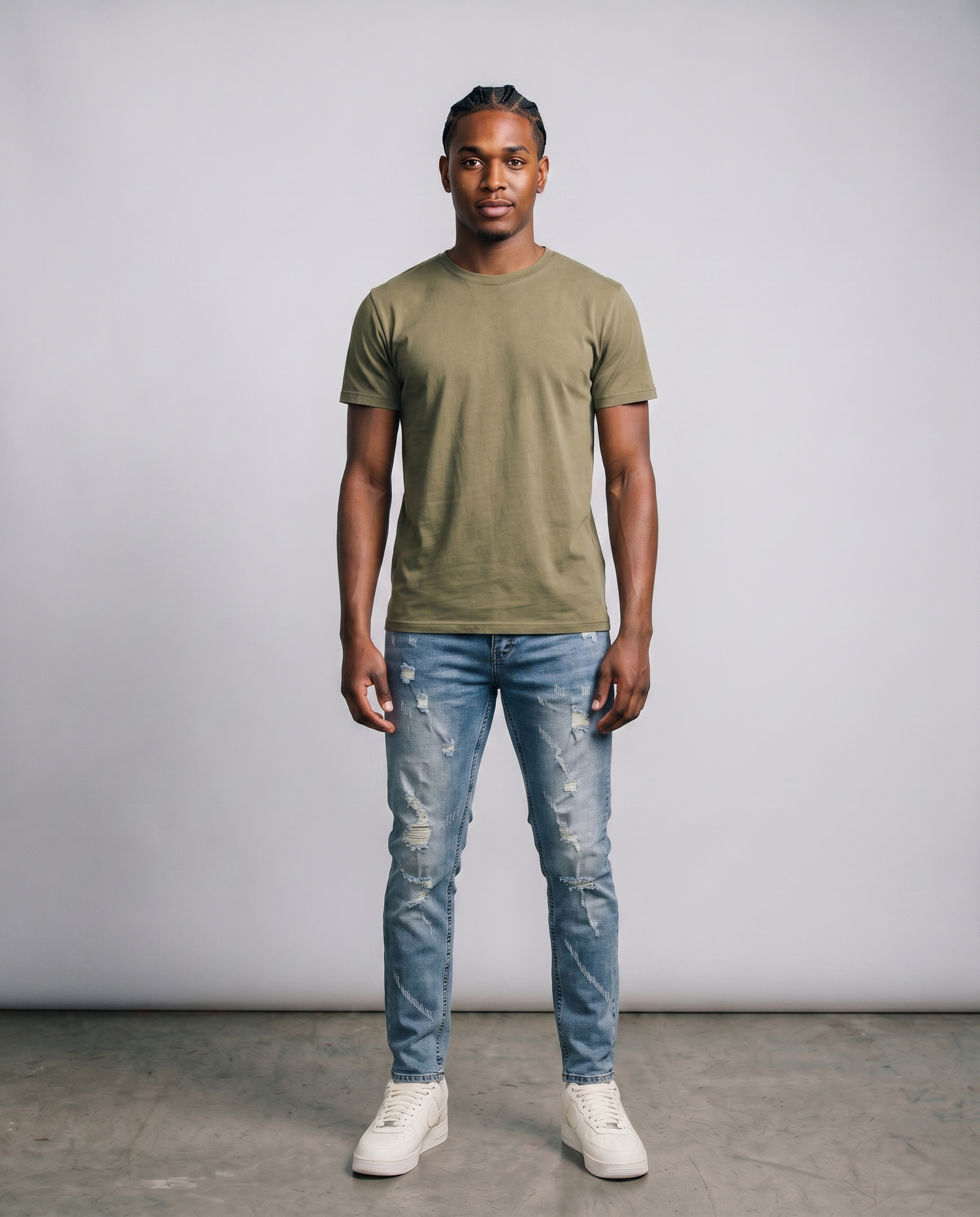 Man wearing a green t-shirt and blue jeans standing against a plain background
